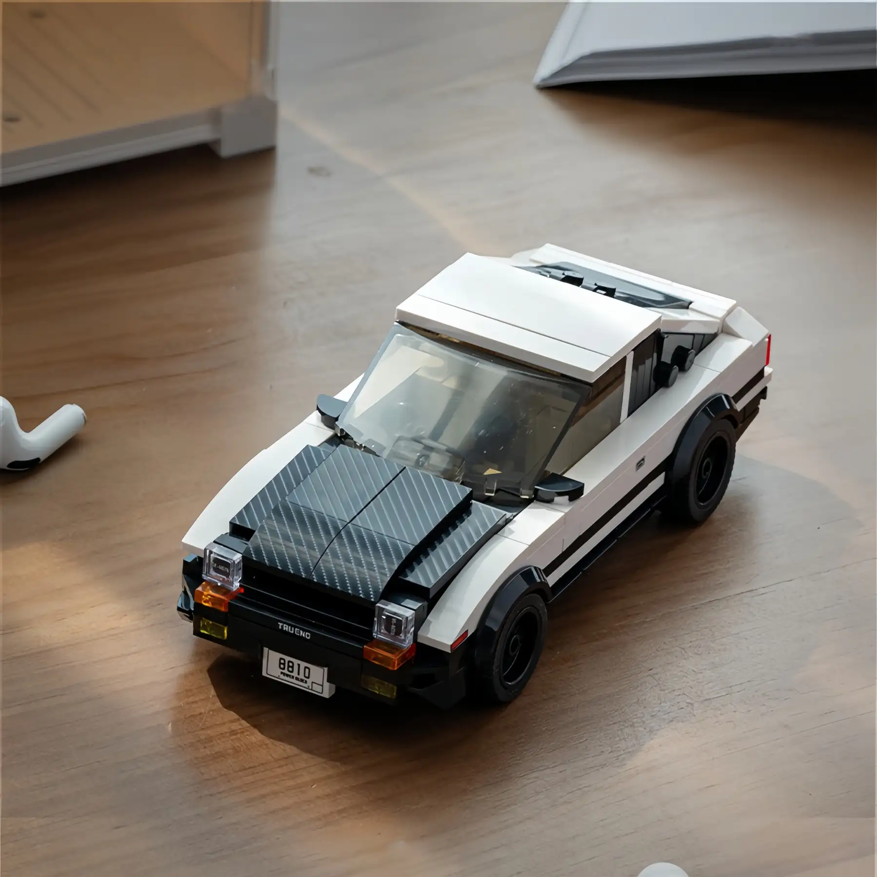 Real-life shot of the assembled Toyota AE86 Trueno brick model car sitting on a wooden tabletop under natural light.