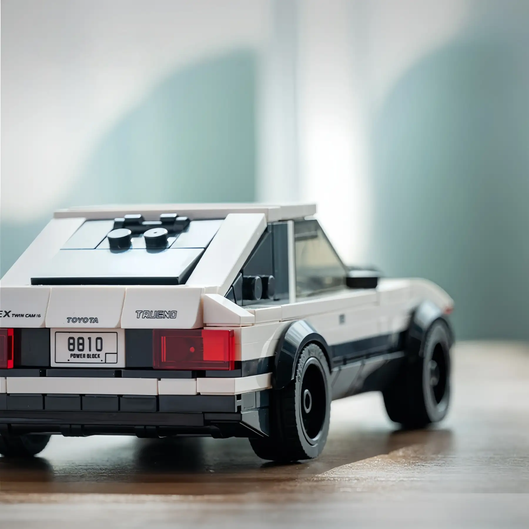 Real-life close-up shot of the Toyota AE86 Trueno brick model car's rear, showing the Toyota Trueno stickers and license plate on a wooden table.
