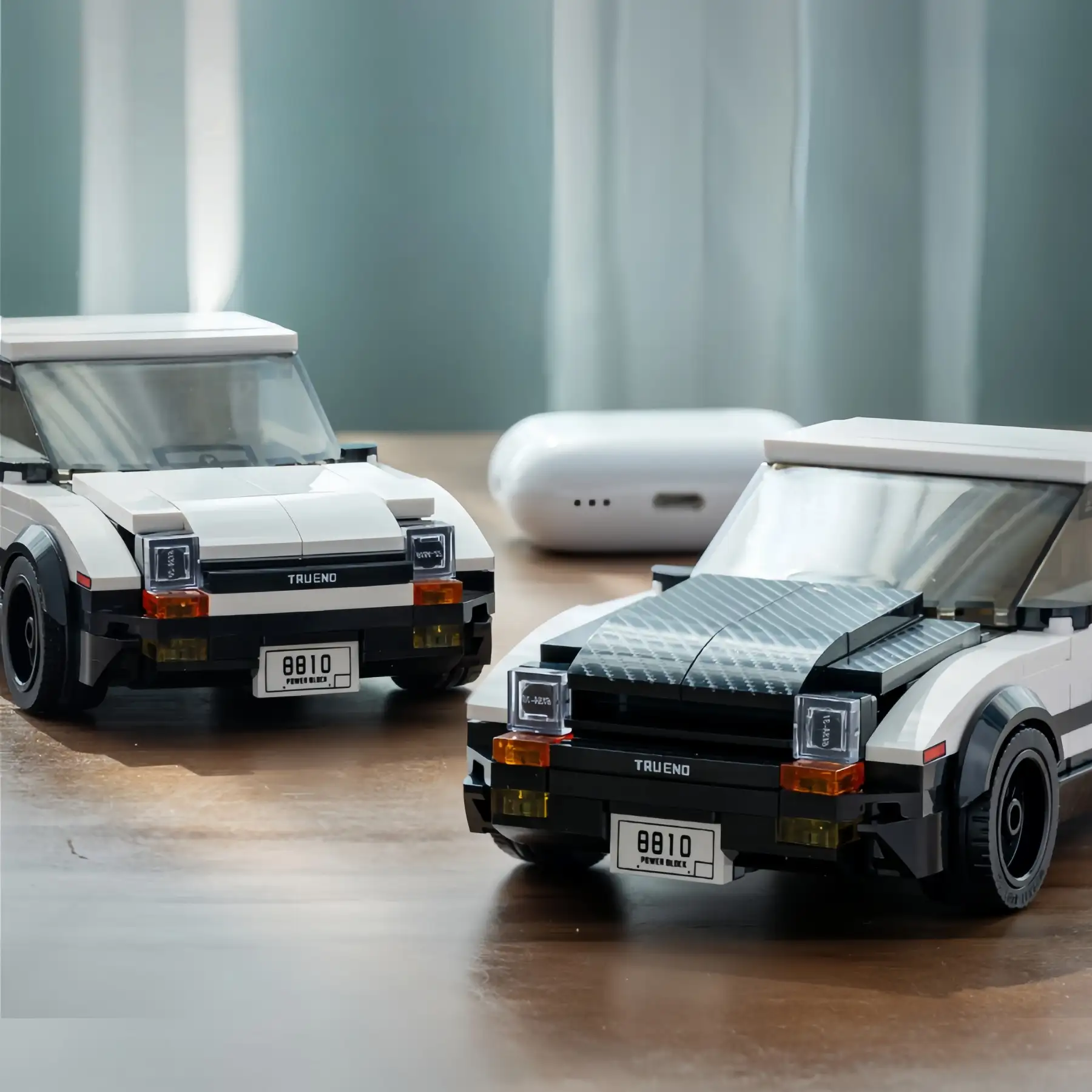 Two Toyota AE86 Trueno brick model cars side by side, showing the white hood version and the carbon fiber pattern hood version.