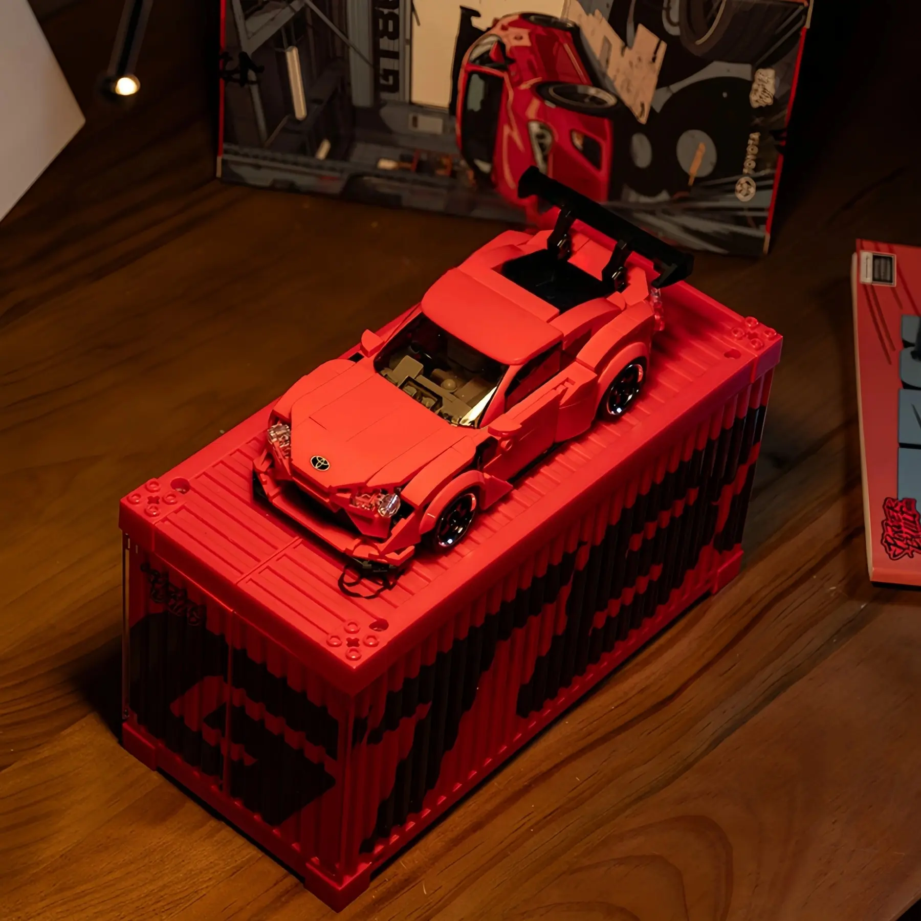 Red Toyota 86 sports car brick model resting on top of its illuminated cargo container display case.